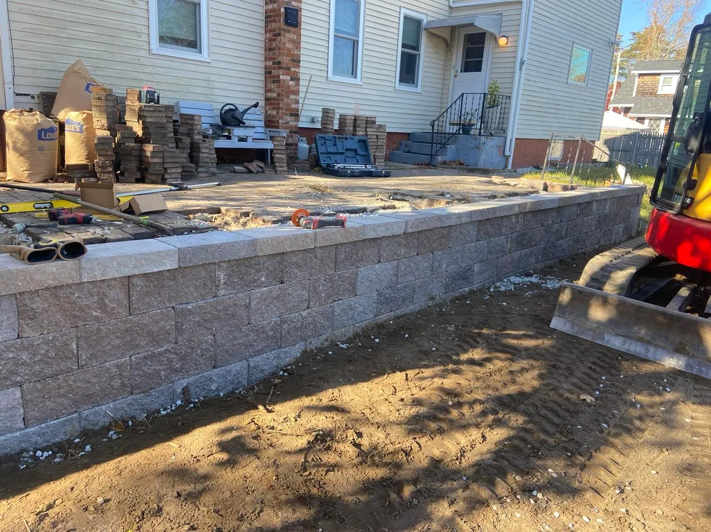 Residential retaining wall construction beside house patio renovation