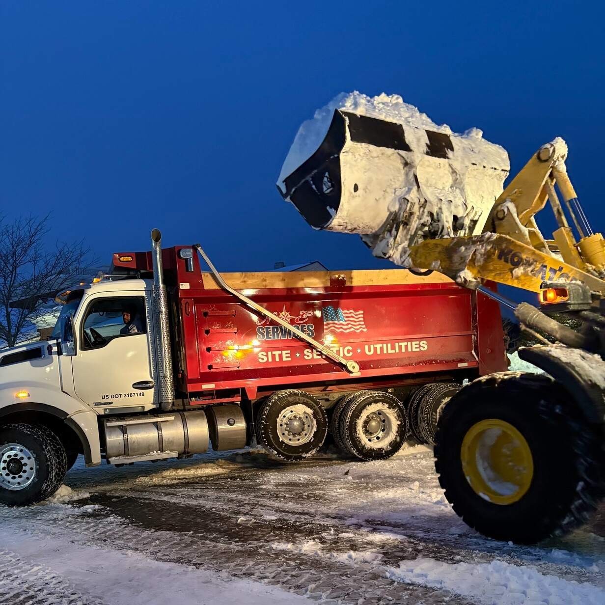 Front loader loading snow into dump truck for snow removal
