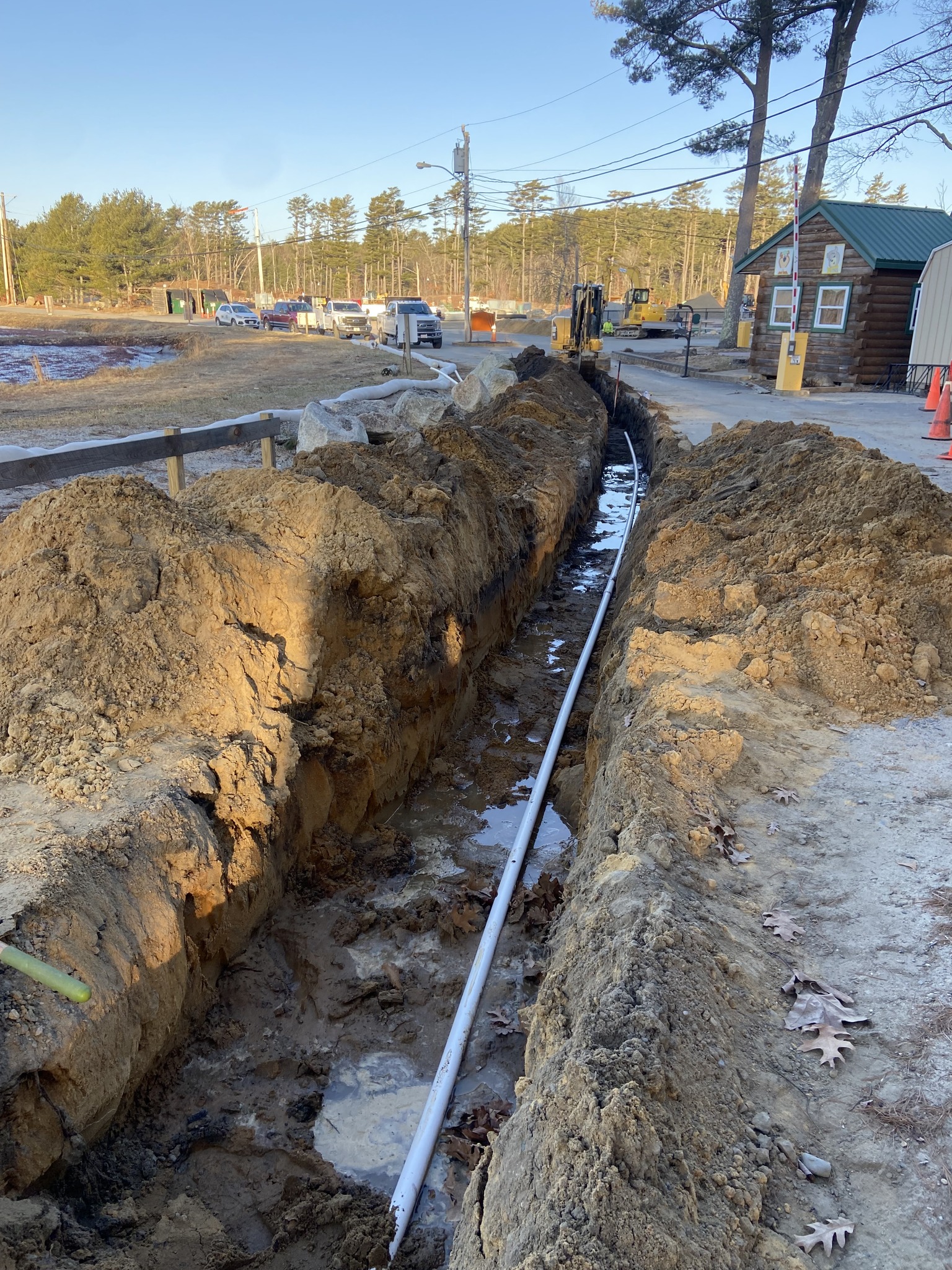 Long trench excavation with pipe installation near roadside utility area